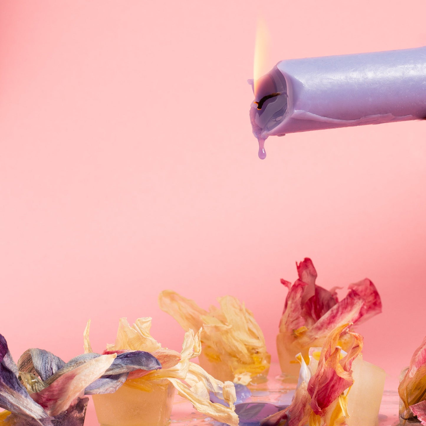 Palava kynttilä kaatamassa vahaa kukkien päälle